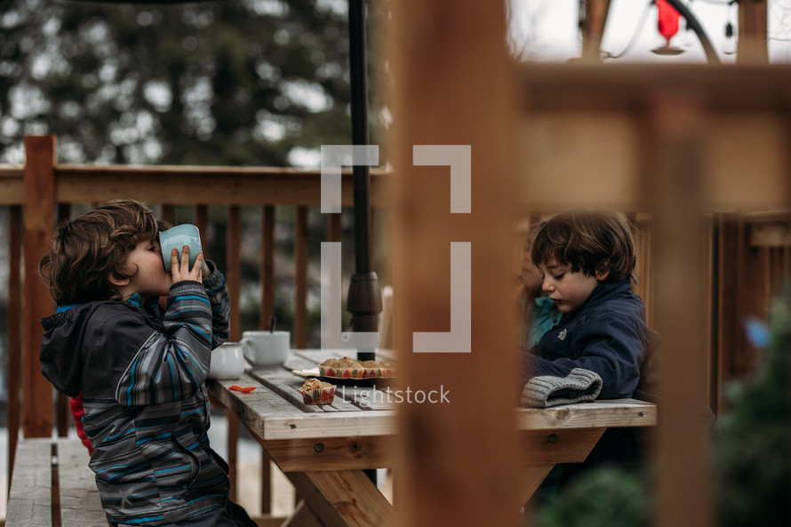boys eating muffins on a back deck 