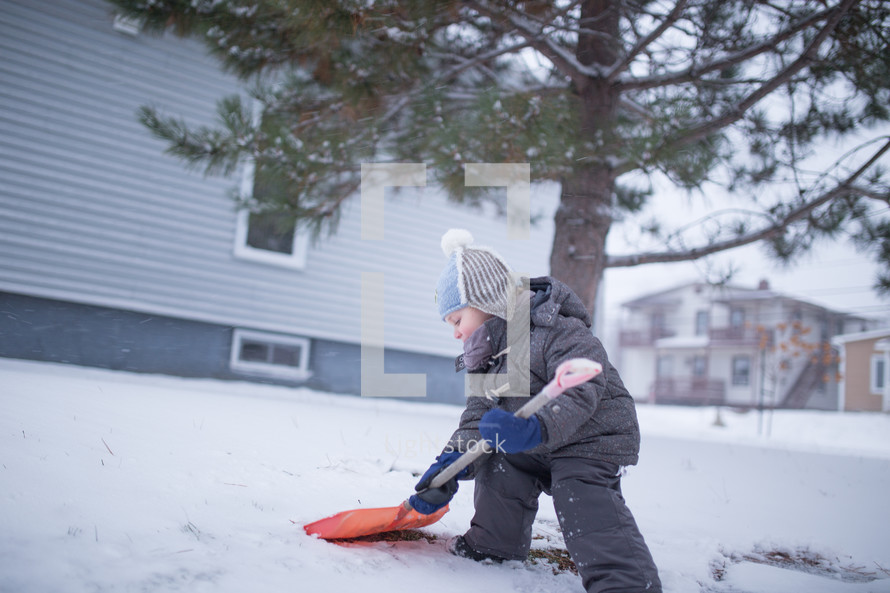 a boy child shoveling snow 