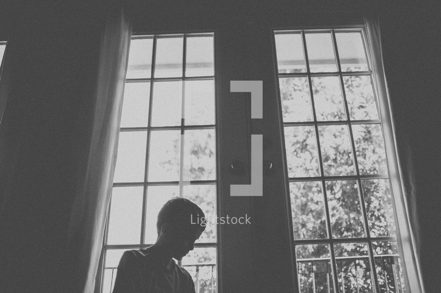 boy standing in front of a window 