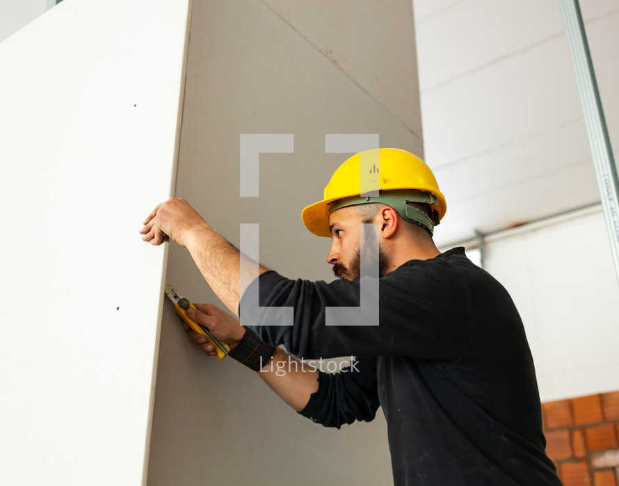 Worker at work in the construction of a plasterboard wall.