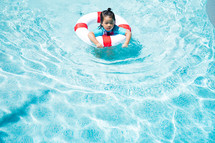 a toddler in an inner tube in a pool 