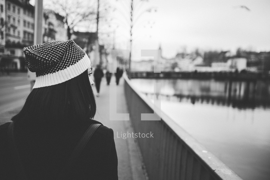 woman walking down a sidewalk near a canal 