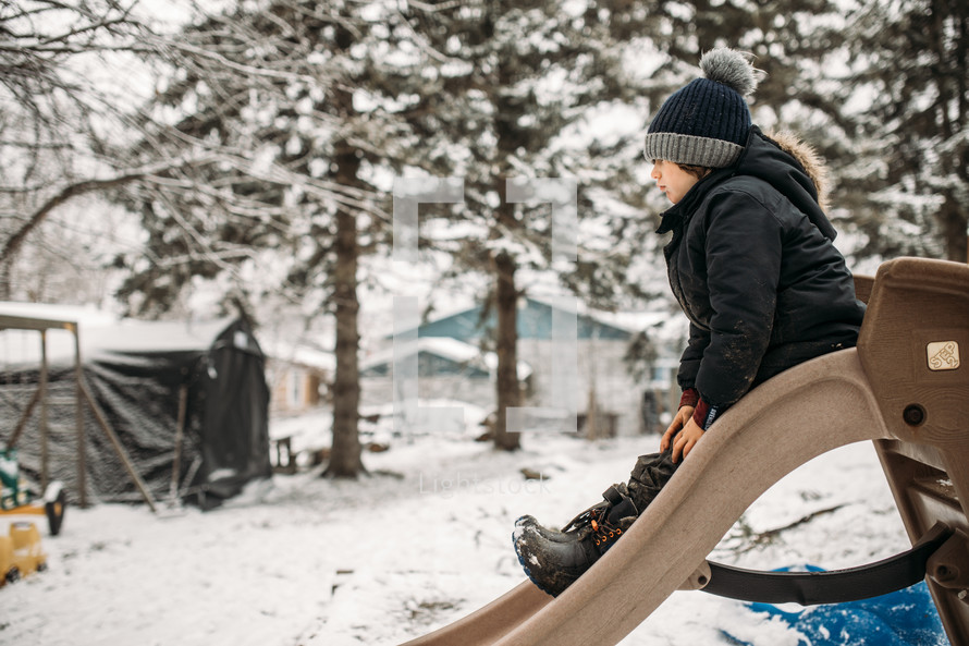 boy going down a slide in winter 