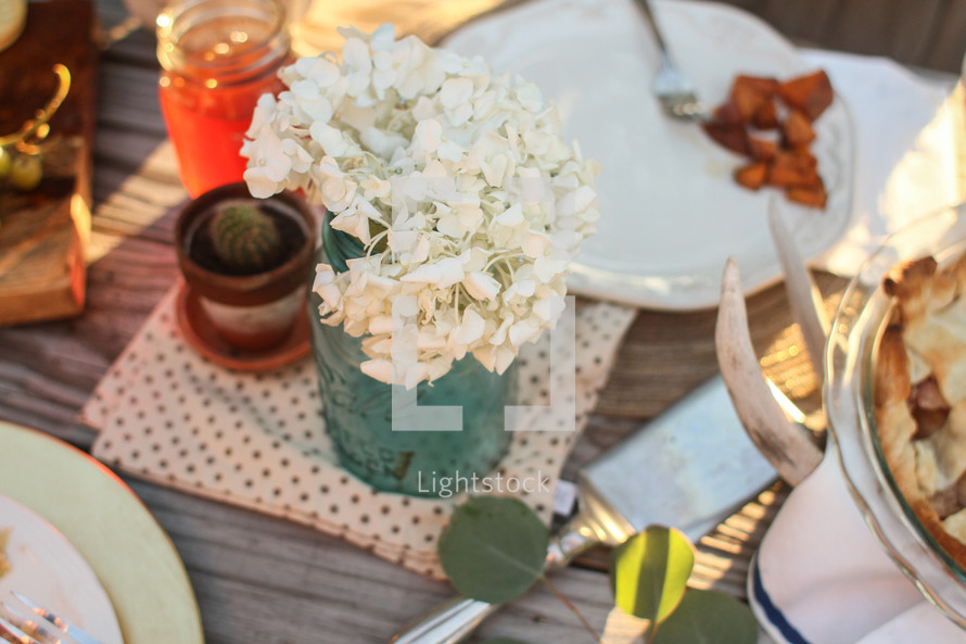 Place settings with  flowers on a picnic table outside.