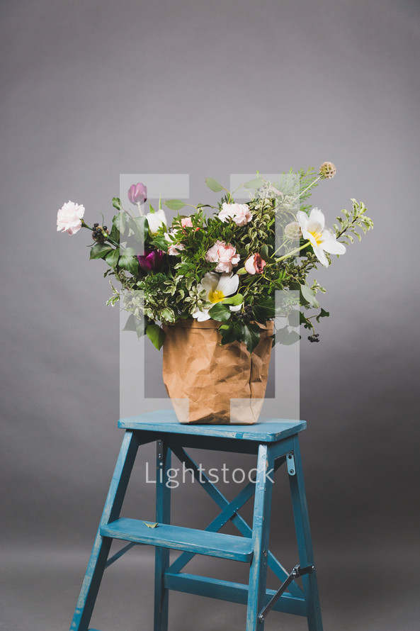 a flower arrangement on a blue ladder 