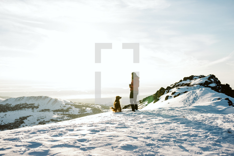 Woman and dog hiking on a snowy mountain