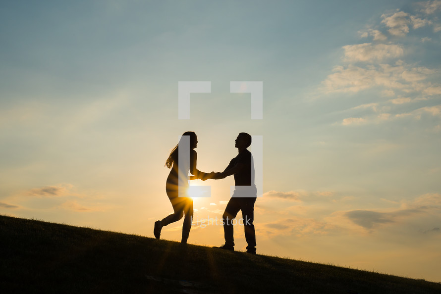 silhouettes of a young happy couple dancing at sunset 