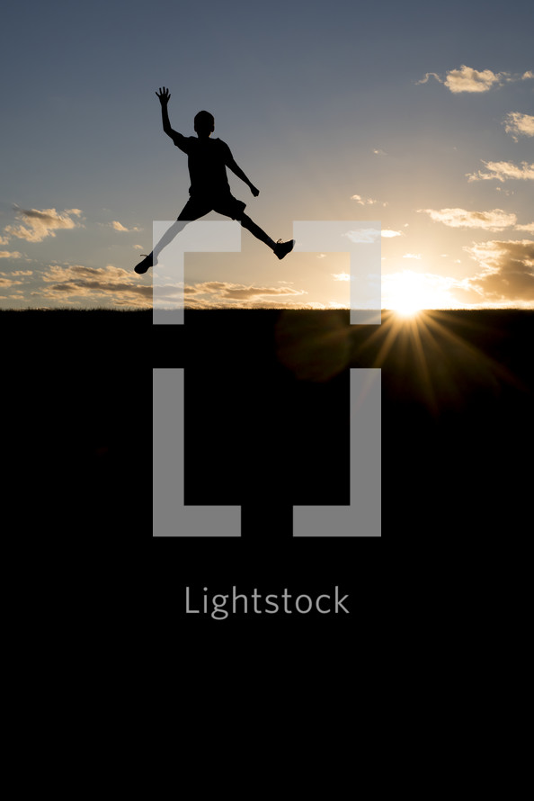 silhouette of a boy jumping in the air 