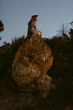 a woman sitting on a rock thinking 