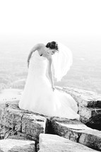 A bride posing on a mountaintop.
