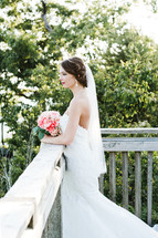 a bride standing on a wooden deck holding a bouquet 