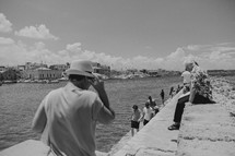 tourists walking along a concrete sea wall at a harbor in Greece 