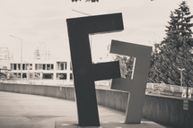 Letter "F" sculpture on a platform at a subway station.