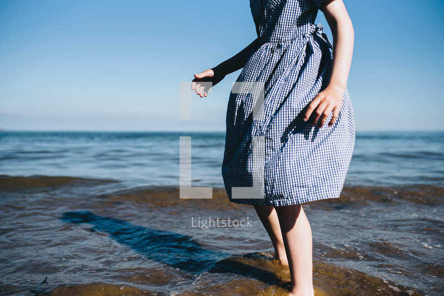 a girl standing in the ocean in a dress 