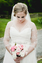 a bride holding a bouquet of flowers and looking down 