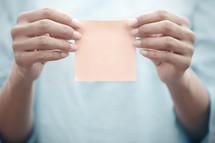 a woman holding up a blank sticking note 