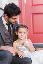 a father and daughter sitting on the steps of a church 