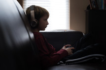 a boy listening to headphones and playing a video game 