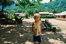 a toddler boy standing barefoot in the dirt 