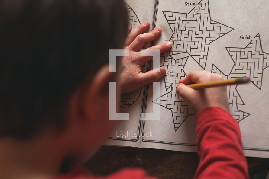 child completing a maze on paper 