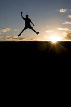 silhouette of a boy jumping in the air 