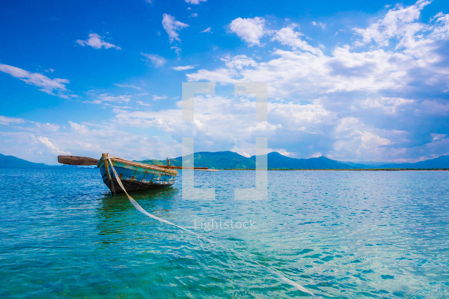 tied boat floating on a turquoise sea 