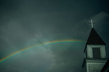 a rainbow in a gray sky and a church steeple 