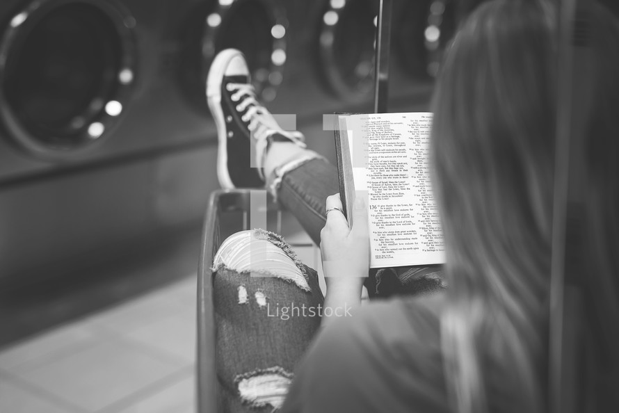 a woman reading a Bible at a laundry mat 