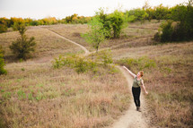 woman walking up hill on a trail 