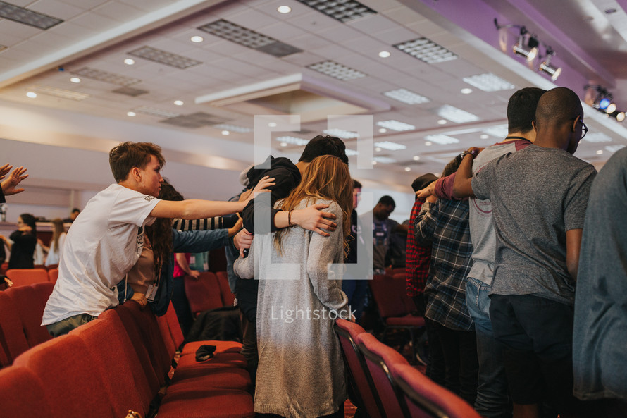 placing hands on others in prayer at a worship service 