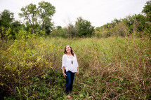 portrait of a young woman standing outdoors in tall grasses 
