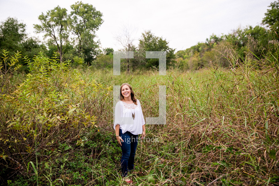 portrait of a young woman standing outdoors in tall grasses 