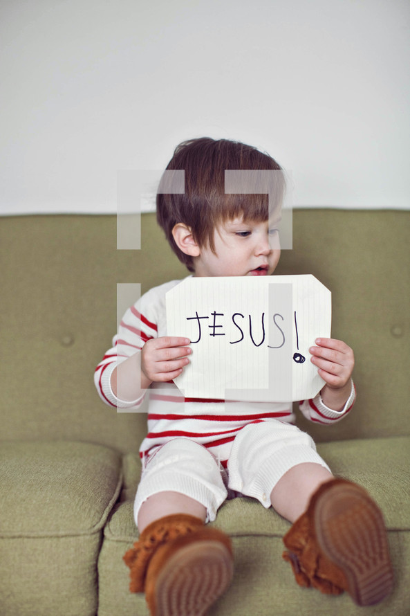 toddler holding a sign that reads Jesus 