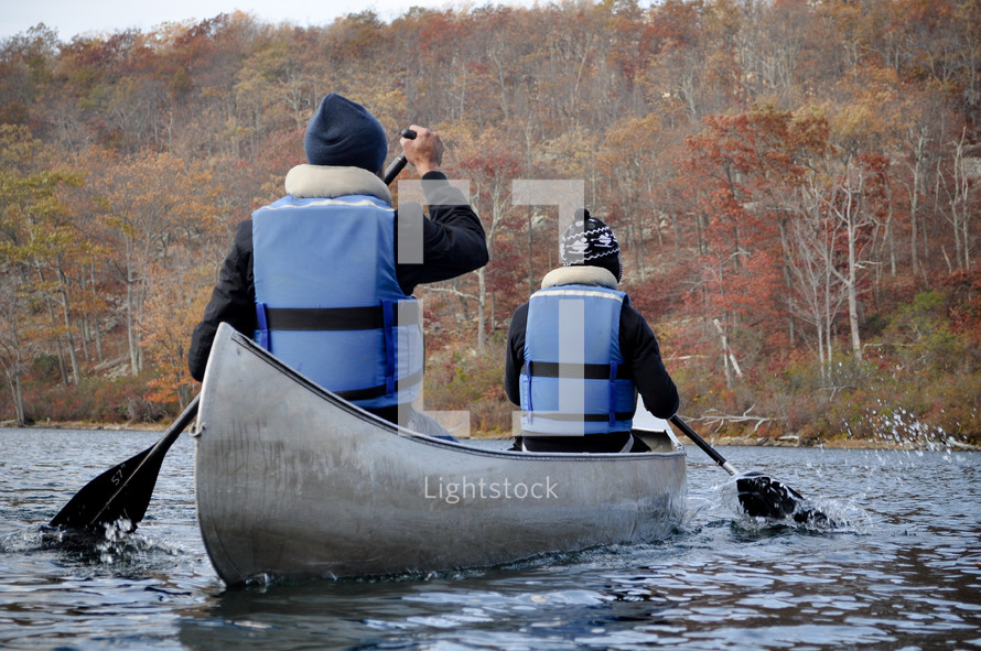 people with life jackets paddling a canoe 