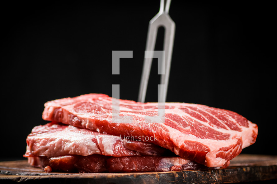 Raw pork steak on a stone board. On a black background. High quality photo