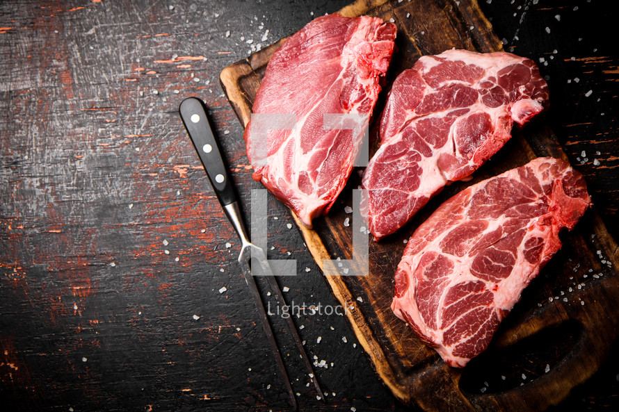 Raw pork steak on a stone board. On a black background. High quality photo