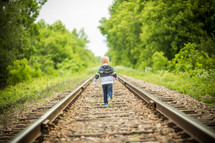 toddler boy running on train tracks 