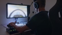 Man playing a flight simulator on the computer, wearing a headset