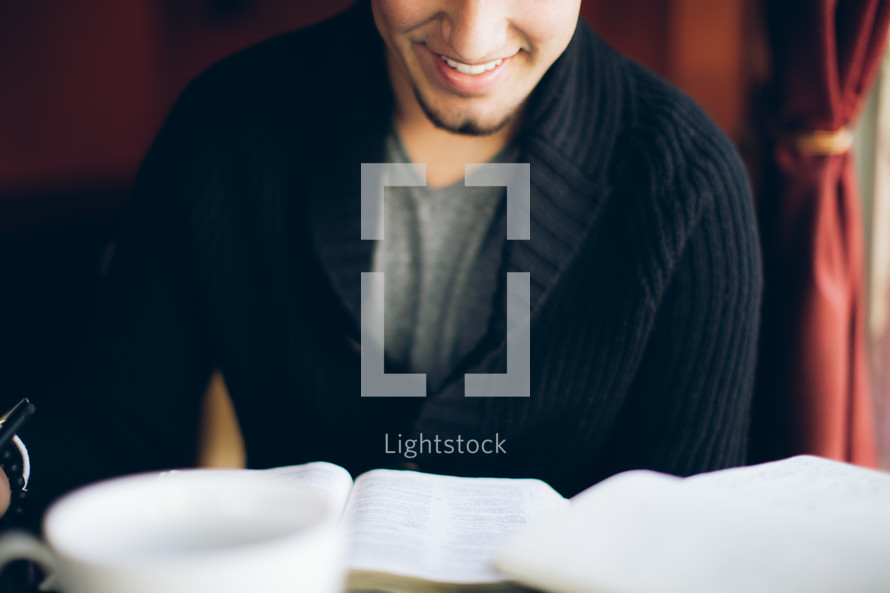 man reading from a Bible and smiling 