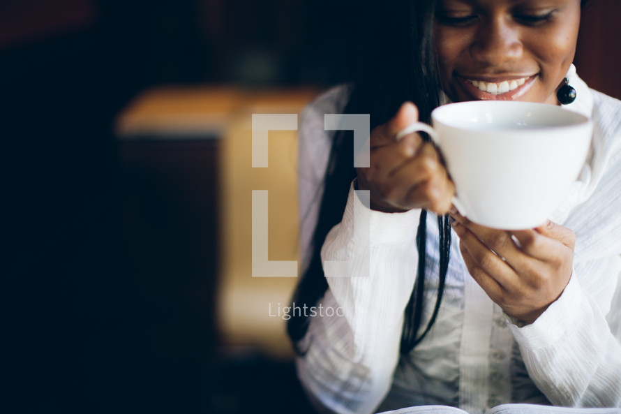 woman holding a coffee mug to her mouth over a Bible
