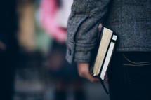 man holding a Bible and journal at his side as he heads to a Bible study
