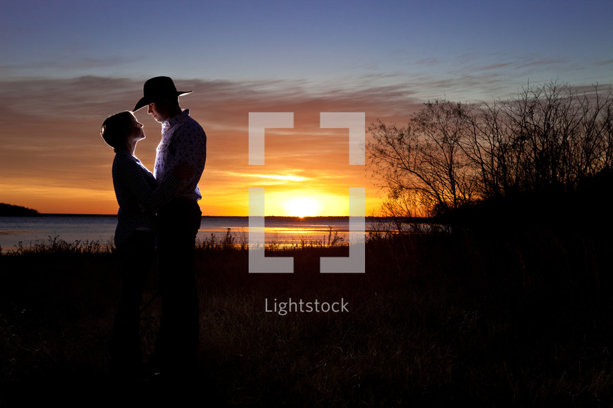 woman and man in a cowboy hat under the glow of a sunset