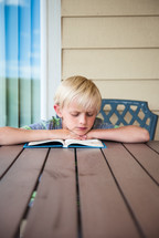 boy child reading a book outdoors 