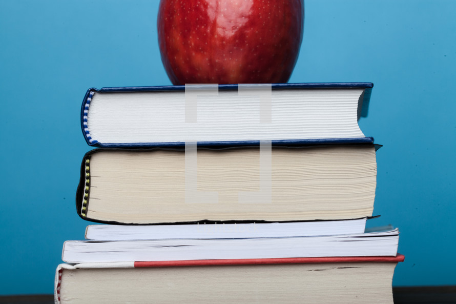 A red apple on top of a stack of books.