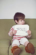 toddler holding a sign that reads Jesus 