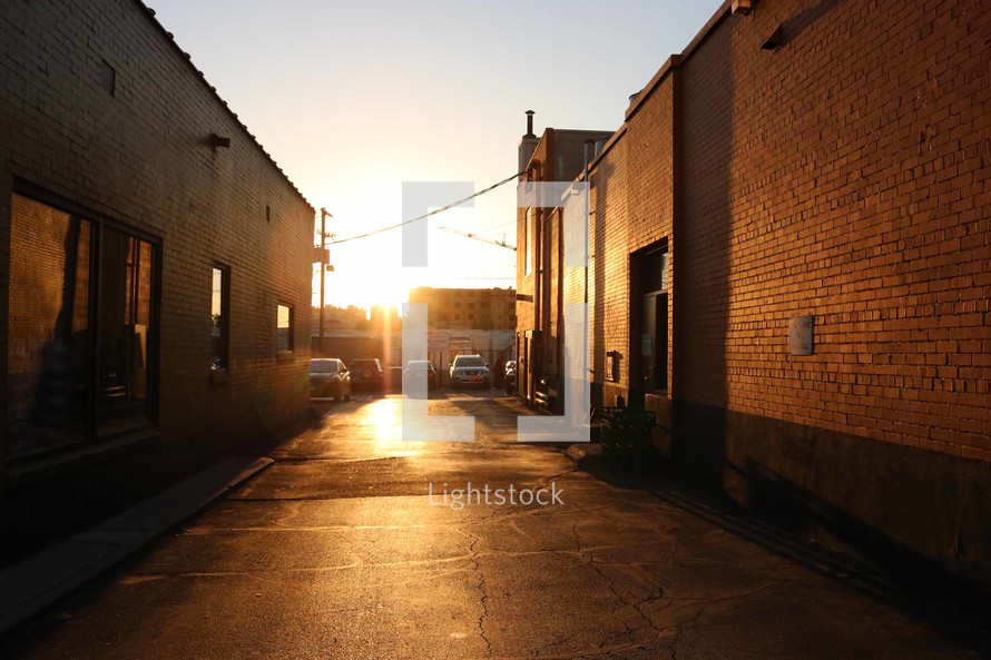 warm sunlight hitting the pavement in an alley 