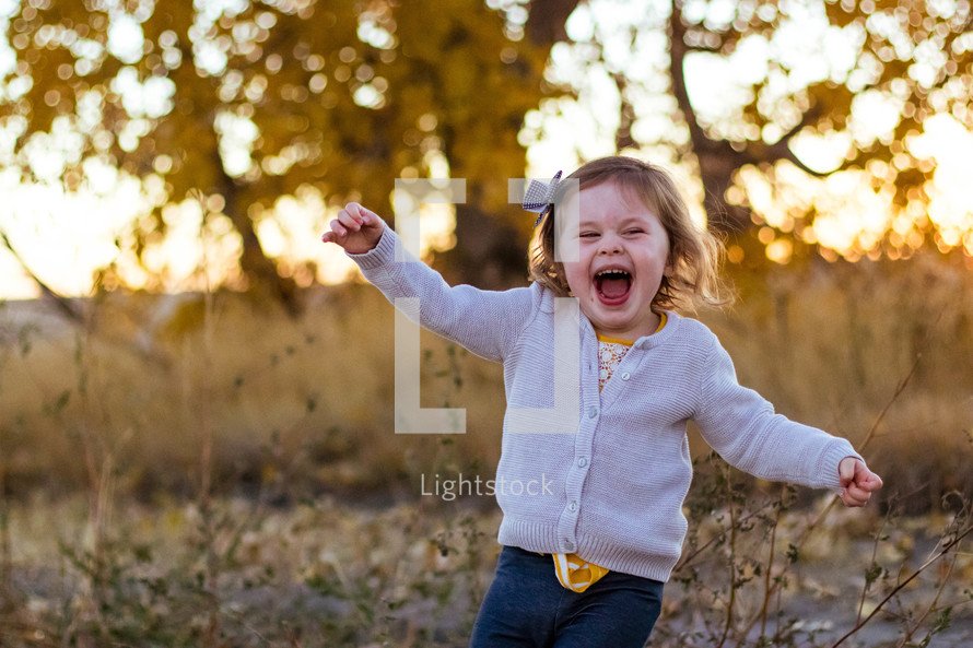 happy toddler girl running outdoors 