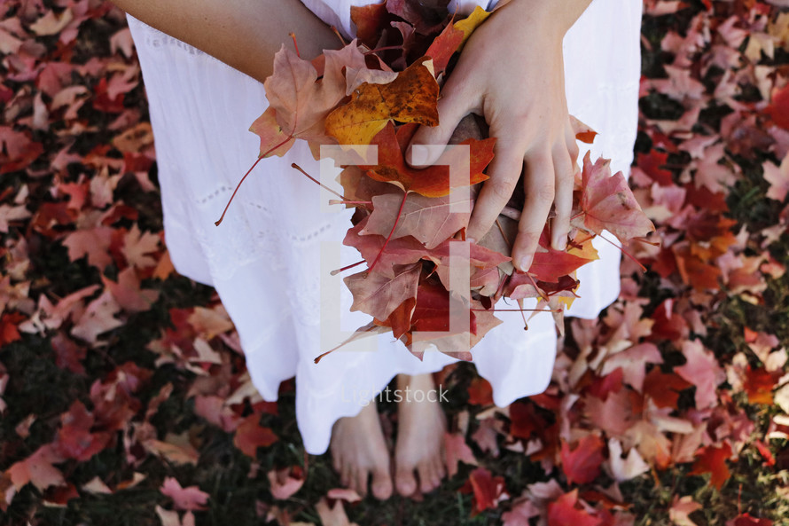 barefoot woman holding fall leaves 