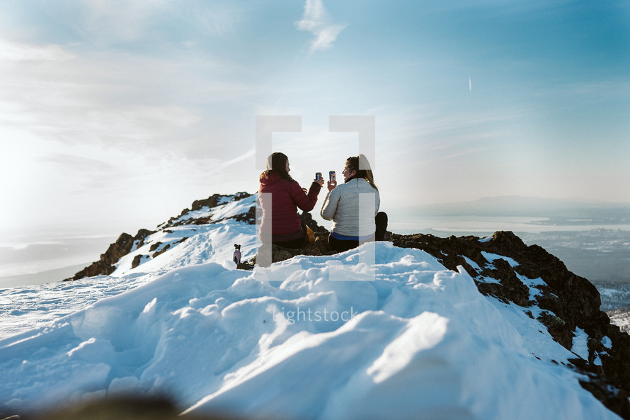 Two woman sharing a beer at the top of a snowy mountain