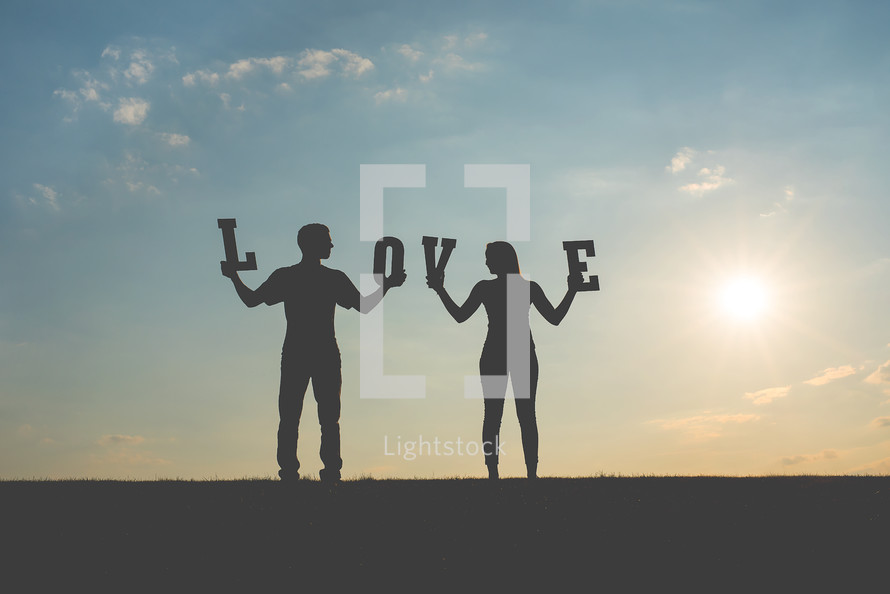 man and woman holding up the word love 
